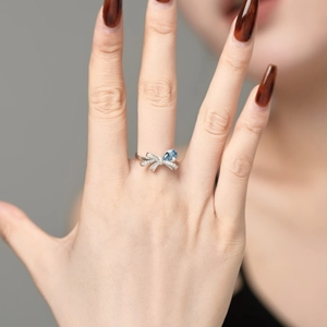 Macro detail of elegant S925 silver ring featuring blue teardrop zircon on model hand