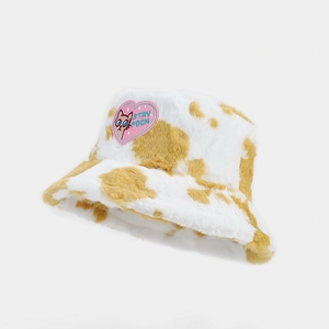 Detailed close-up of cow print plush bucket hat featuring a pink heart cat embroidery