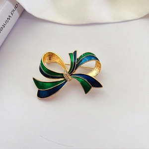 Detailed macro of vintage palace style enamel bow brooch with blue and green dolphin oil details