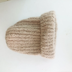 Detail shot of the textured beige bouclé knit beanie with a thick rolled cuff design