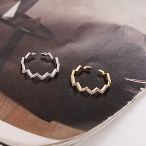 Macro detail of wave zigzag rings in gold and silver with zircon micro-pave on a magazine