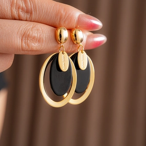 Close-up of gold-plated resin earrings with engraved hand made text on metal part