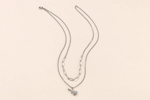 Macro detail of silver double-layered necklace featuring a creative guitar-shaped pendant