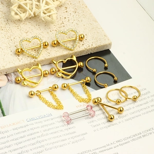 Detailed close-up of mixed heart and tassel nipple rings on a styled magazine surface