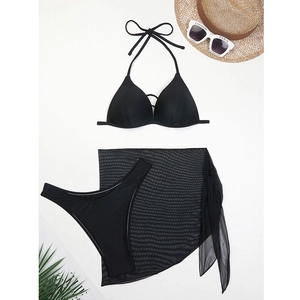 Flat lay of black three-piece bikini set with sheer mesh sarong and summer beach accessories