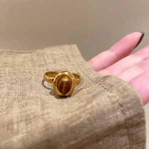 Detail of a vintage golden oval ring with tiger eye stone held over linen fabric