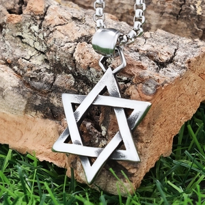 Macro shot of silver stainless steel Star of David pendant on natural wood and grass