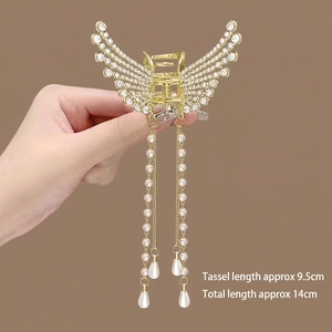 Detailed view of golden wing hair claw clip with crystal rhinestones and pearl tassels