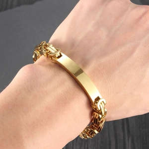 Close-up of golden titanium steel Byzantine bracelet with a polished metal nameplate on wrist