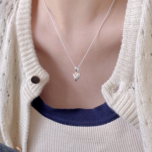 Close-up of minimalist 925 sterling silver irregular heart pendant on a thin link chain