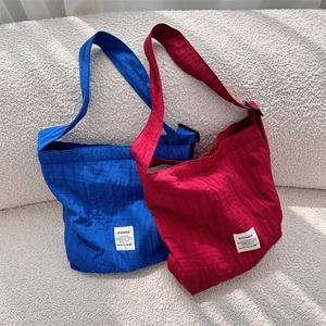 Detailed view of pleated texture on blue and red canvas shoulder bags on a sofa