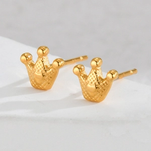 Detailed macro view of gold crown-shaped stud earrings with textured polka dot pattern
