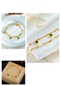 Close-up of double-layer gold chain with green heart pendants and crystal beads