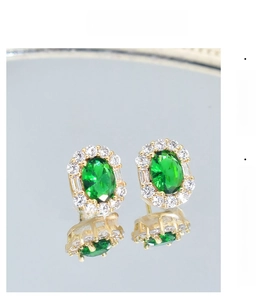 Close-up of vintage emerald cut green zircon earrings with surrounding small diamonds