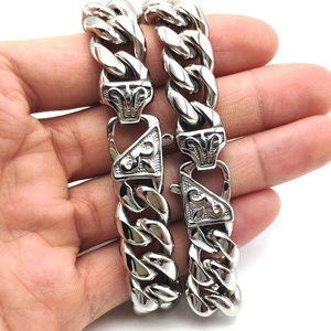 Detailed close-up of a silver stainless steel Cuban link bracelet with engraved vine clasp
