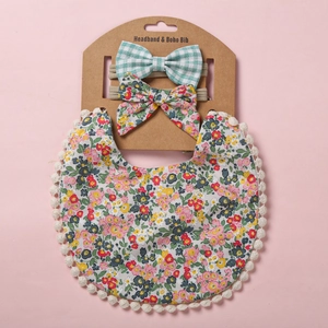 Détail d'un bavoir bébé boho à fleurs avec pompons et deux bandeaux à nœuds assortis