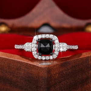 Macro shot of cushion cut black gemstone ring with halo diamonds on red velvet