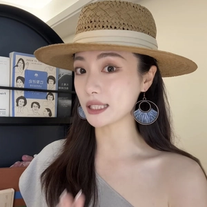 Elegant bohemian circle earrings with blue woven detail worn by model with straw hat