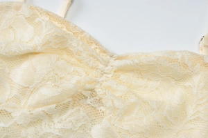 Detail shot of the off-white floral lace texture and pleated fabric on the tube top dress