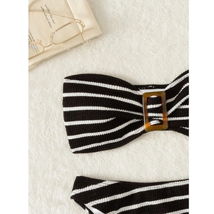 Detail of striped bikini top featuring textured fabric and an amber buckle on white rug