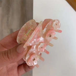 Close-up of pink and beige acetate flower hair claw clip with golden beads