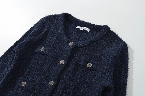 Dettaglio della giacca in tweed blu navy con bottoni dorati e trama del tessuto intrecciato