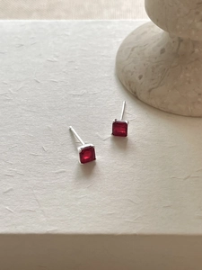 Close-up of square cut red zircon stud earrings with silver four-claw setting