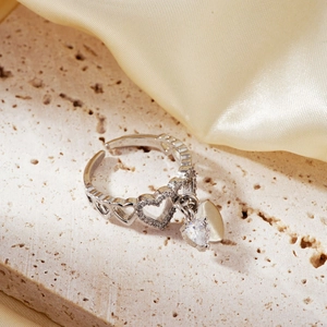Elegant silver heart ring with a zircon pendant on a textured beige stone background