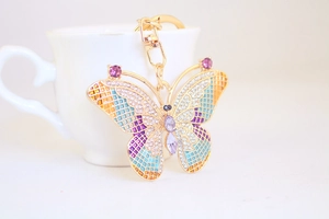 Detail of colorful rhinestone butterfly keychain with gold plating and blue enamel finish