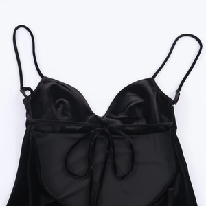 Vue à plat d'un caraco noir en satin à col en V avec un nœud délicat et une texture soyeuse