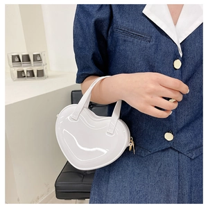 Detailed view of a mini heart-shaped handbag in glossy white with metal zipper and handle