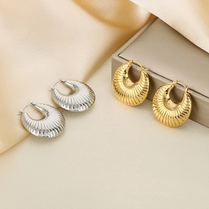 Detail of gold and silver ribbed U-shaped stainless steel hoop earrings on silk
