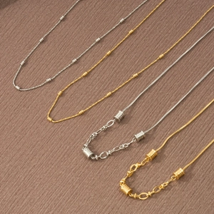 Dettaglio di quattro collane in acciaio al titanio oro e argento con ciondoli a cuore