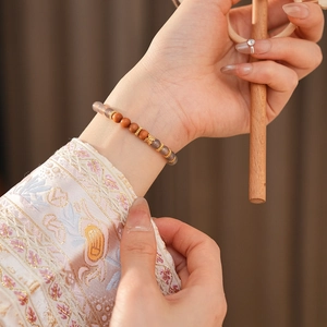Détail d'un bracelet en bois de santal avec pierres d'agate et papillon doré au poignet