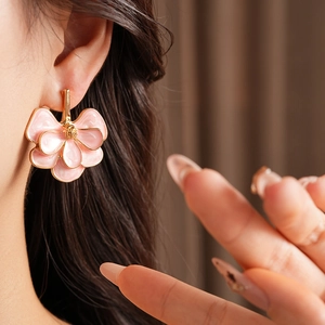 Close-up of vintage pink flower earrings with gold edges on a female model