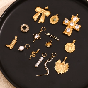 Flat lay of diverse 18K gold plated charms including bows, pearls and Mama pendant