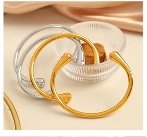 Bracciali rigidi a goccia color oro e argento con finitura metallica a specchio