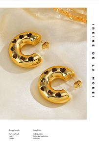 Detailed close-up of 18K gold-plated C-shaped earrings with hollow heart pattern detailing