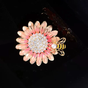 Detailed close-up of a pink enamel daisy brooch with a crystal honeybee and pearl accents