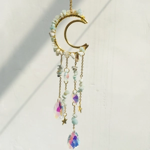 Detail of crescent moon suncatcher with golden chains, teal stones and crystal pendants