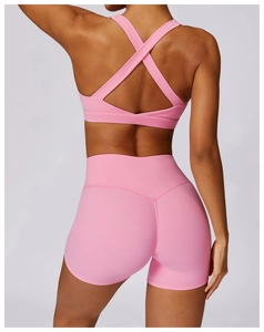 Close-up of pink yoga set featuring crisscross back sports bra and high-waist shorts