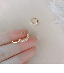 Macro shot of gold-plated sterling silver huggie earrings with small white pearls