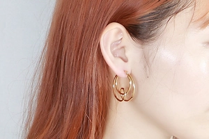 Detailed view of gold plated double hoop knot earrings worn on female model's ear