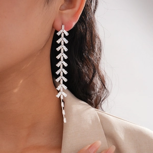 Detail of leaf tassel earrings with baguette-cut zircons worn by model for elegant look