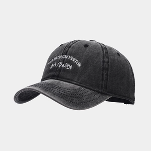 Close-up of the museum visitor embroidery on dark grey washed denim baseball cap