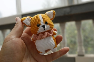 Detail view of handmade crochet Corgi dog keychain in orange and white yarn