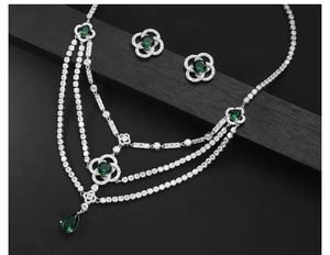 Detail of emerald green jewelry set with layered necklace and flower earrings