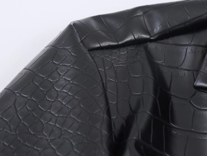 Macro view of black faux leather with detailed crocodile embossed texture on PU coat