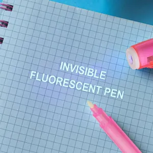 Pink invisible ink pen with UV light cap showing glowing blue text on a notebook