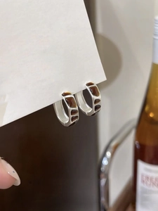 Macro detail of silver geometric hoop earrings with amber enamel on a display card